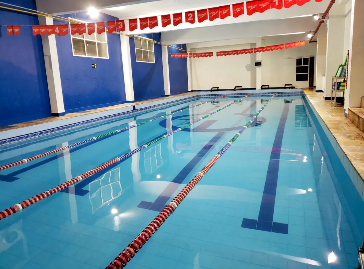 Piscina coberta de raias da Academia Estilo, com paredes azuis e bandeirinhas numeradas